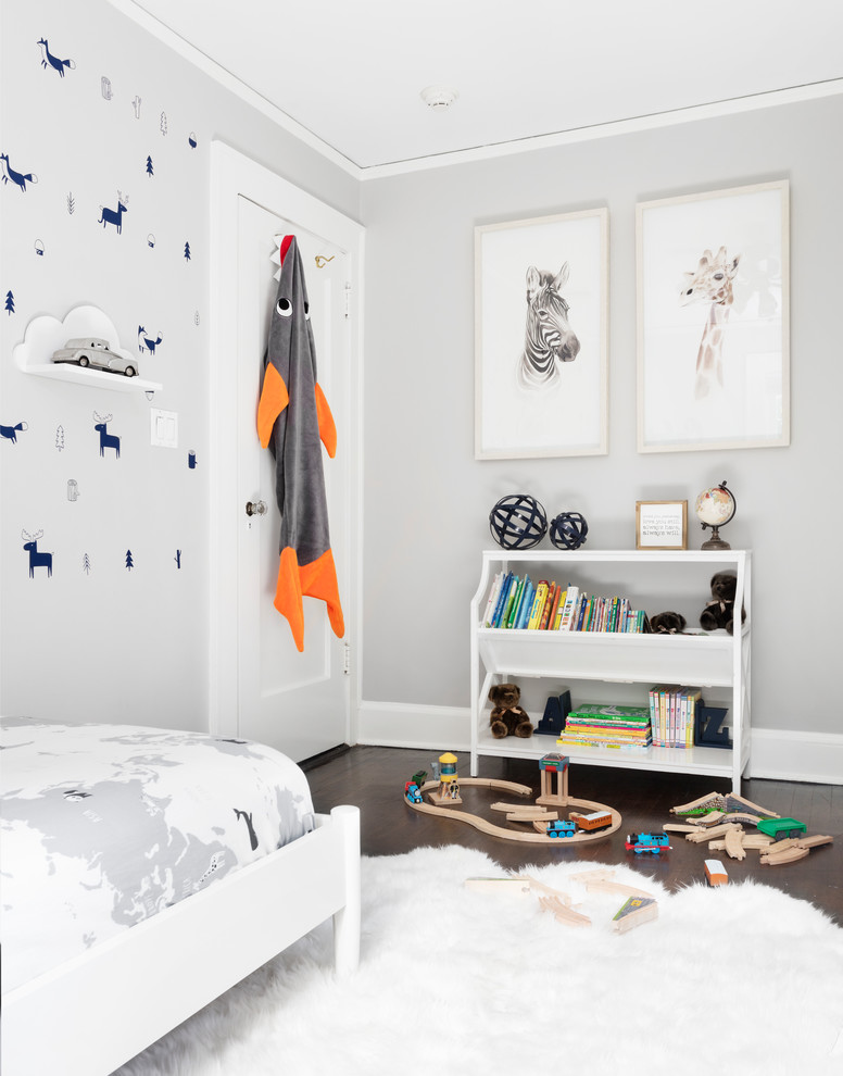 Small contemporary toddler’s room for boys in New York with grey walls, dark hardwood flooring and brown floors.