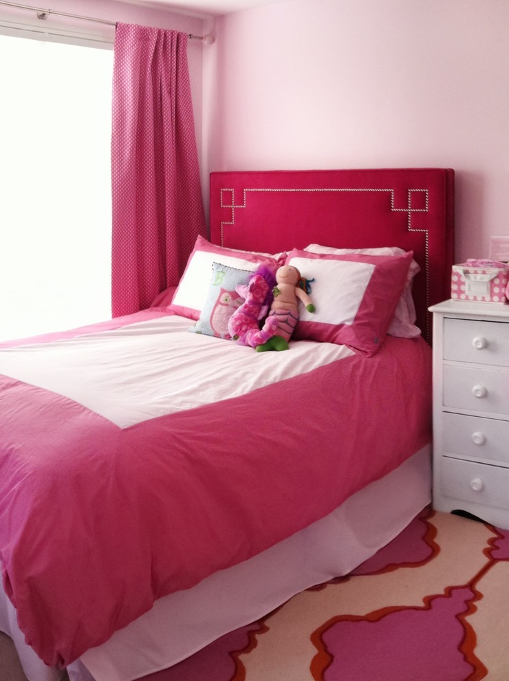 This is an example of a large contemporary children’s room for girls with pink walls, carpet and beige floors.