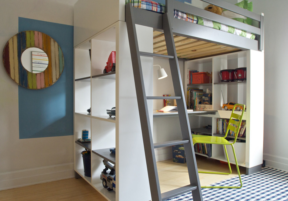 This is an example of a contemporary gender neutral kids' study space in New York with white walls, light hardwood flooring and beige floors.
