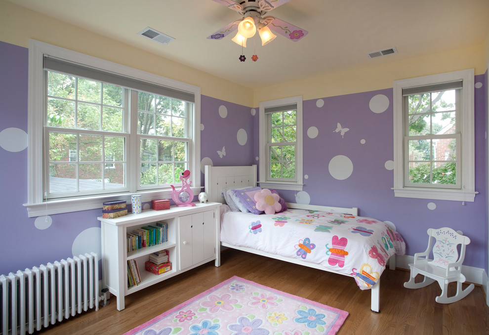 Design ideas for a traditional toddler’s room for girls in DC Metro with purple walls and medium hardwood flooring.