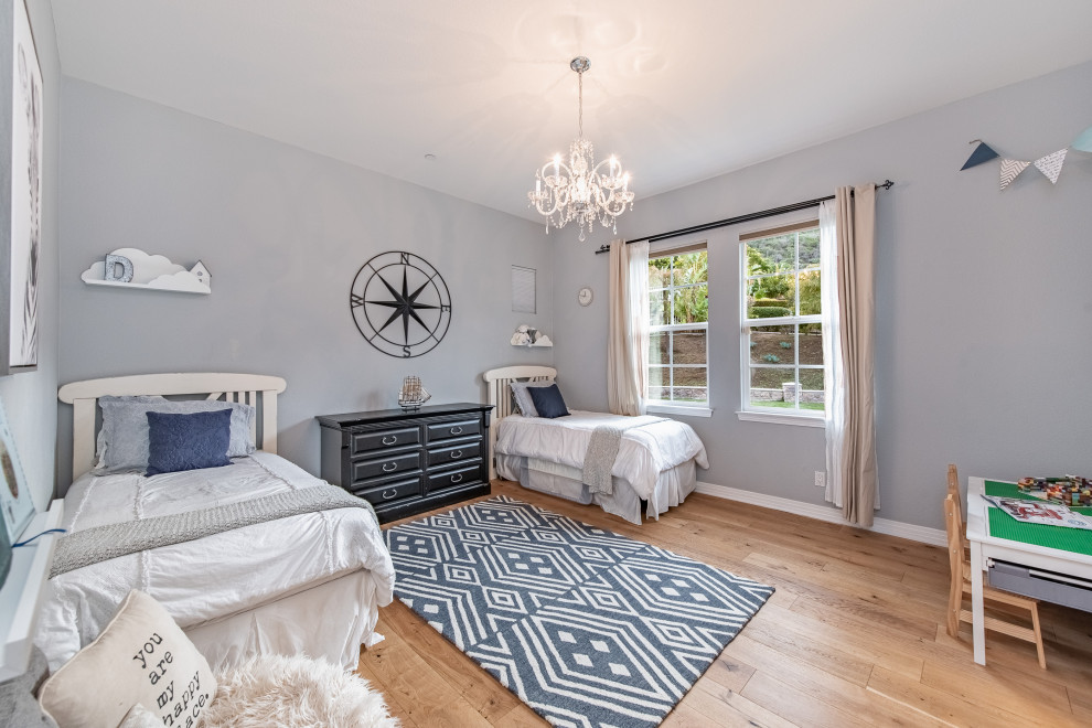 Foto på ett mycket stort medelhavsstil pojkrum kombinerat med sovrum och för 4-10-åringar, med blå väggar, ljust trägolv och beiget golv