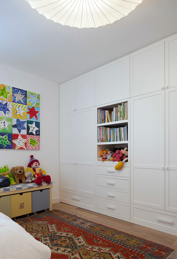 Foto di una cameretta per bambini da 4 a 10 anni contemporanea di medie dimensioni con pareti bianche e pavimento in legno massello medio