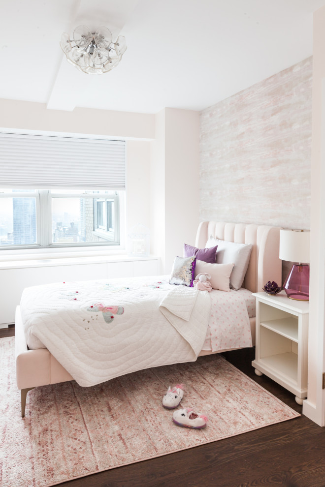 This is an example of a medium sized contemporary children’s room for girls in New York with pink walls, medium hardwood flooring and brown floors.