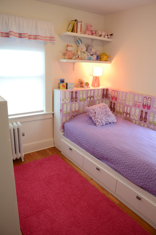 Immagine di una piccola cameretta per bambini minimalista con pareti bianche e pavimento in legno massello medio