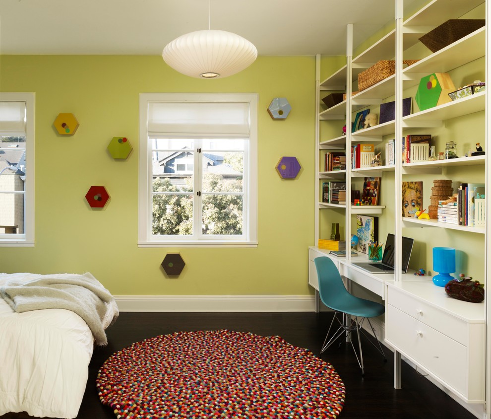 Modern inredning av ett barnrum kombinerat med skrivbord, med mörkt trägolv och gröna väggar
