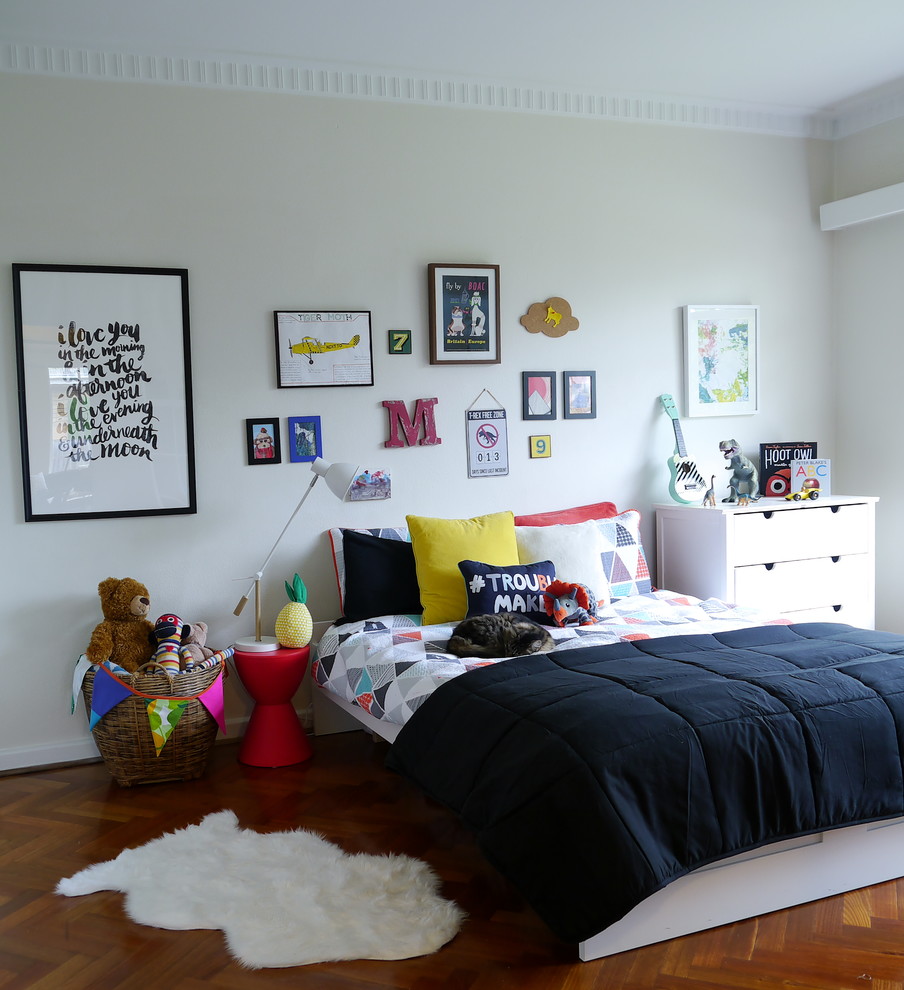 Cette photo montre une chambre neutre de 4 à 10 ans chic avec un mur blanc et un sol en bois brun.