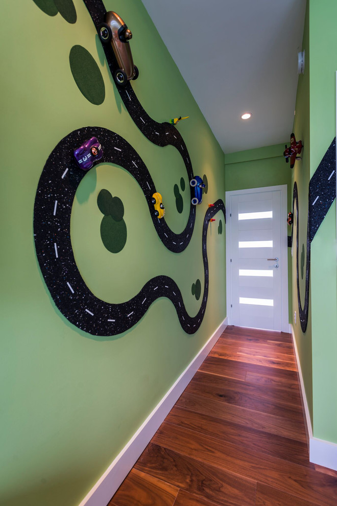 Inspiration pour une chambre d'enfant de 1 à 3 ans design de taille moyenne avec un mur vert et un sol en bois brun.