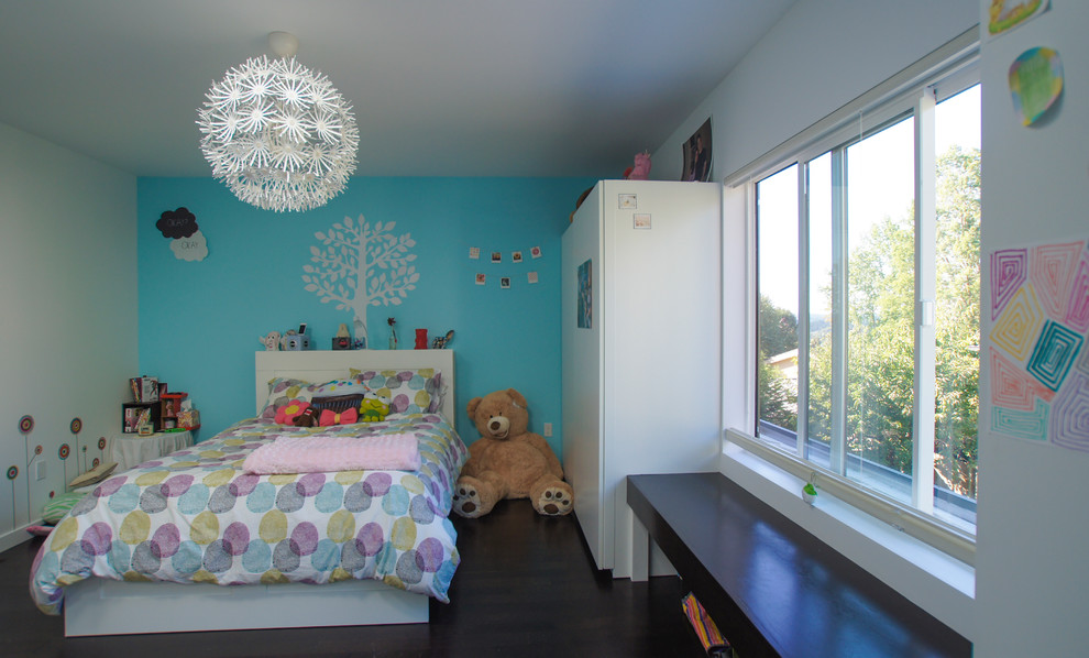 Cette photo montre une chambre d'enfant de 4 à 10 ans moderne de taille moyenne avec un mur bleu et parquet foncé.