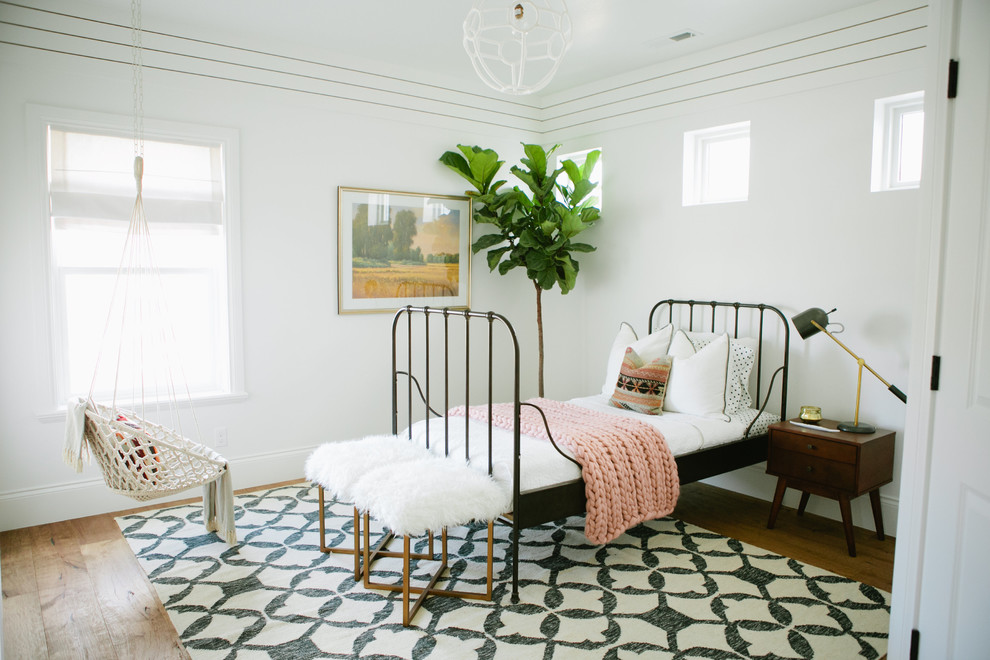 Modelo de dormitorio infantil de estilo de casa de campo con paredes blancas y suelo de madera en tonos medios