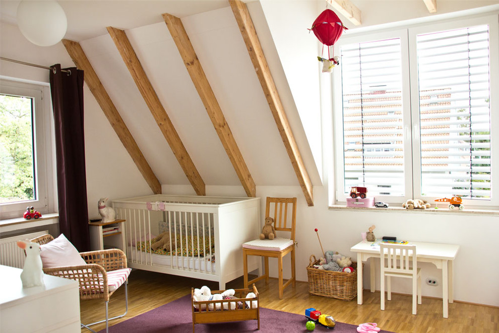 Inredning av ett modernt könsneutralt småbarnsrum kombinerat med sovrum, med vita väggar och mellanmörkt trägolv