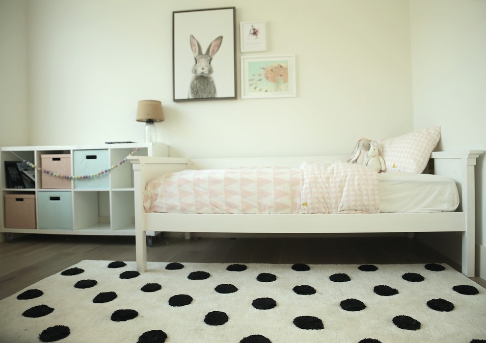 Esempio di una cameretta per bambini da 4 a 10 anni minimalista di medie dimensioni con pareti bianche, pavimento in legno massello medio e pavimento marrone
