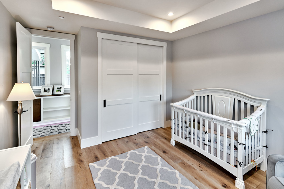 Inspiration för mellanstora klassiska könsneutrala småbarnsrum kombinerat med sovrum, med grå väggar och ljust trägolv