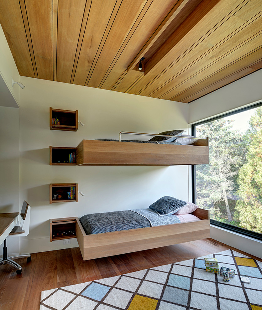 Immagine di una cameretta per bambini da 4 a 10 anni minimal con pareti bianche e pavimento in legno massello medio