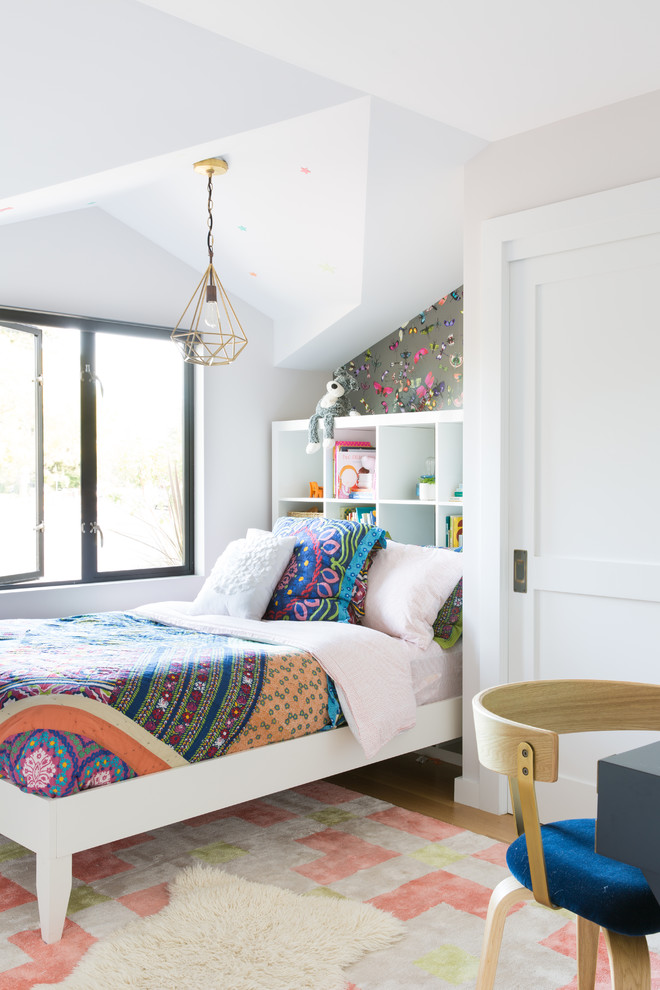 Klassisk inredning av ett flickrum kombinerat med sovrum, med vita väggar och mellanmörkt trägolv