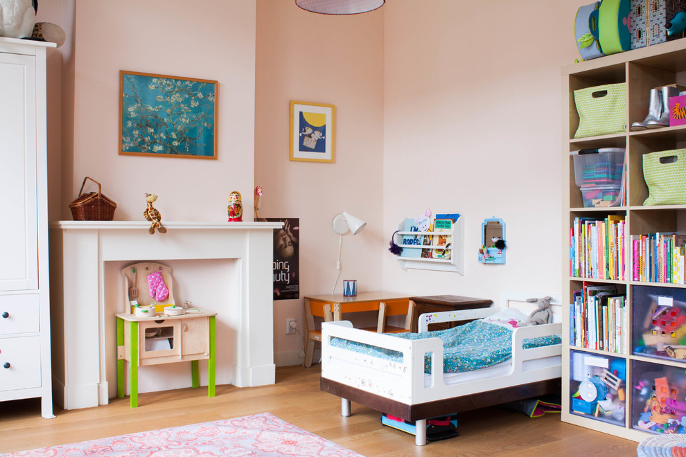 Modelo de dormitorio infantil de 1 a 3 años bohemio grande con paredes rosas y suelo de madera en tonos medios