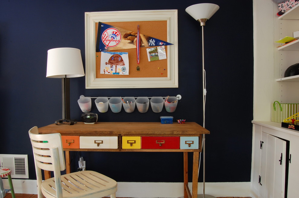 Cette image montre une chambre d'enfant rustique avec un bureau et un mur bleu.