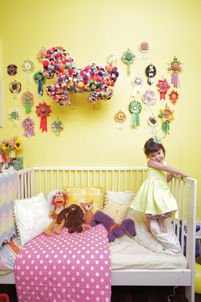 Réalisation d'une chambre d'enfant de 1 à 3 ans bohème avec un mur jaune et parquet foncé.