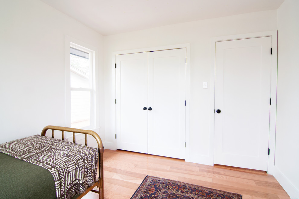 Photo of a medium sized retro gender neutral children’s room in Denver with white walls and light hardwood flooring.