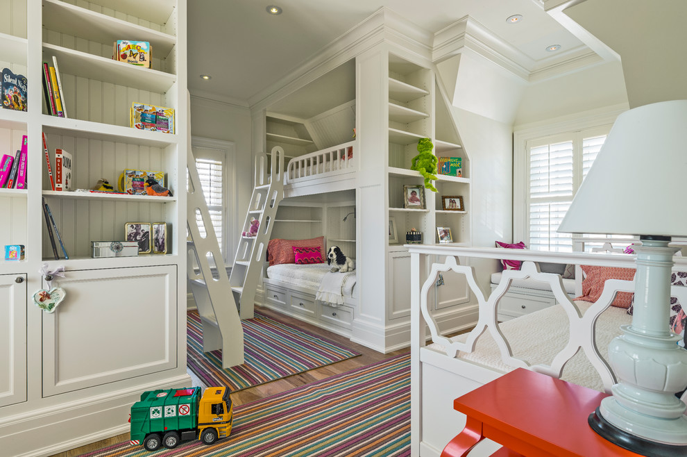 Idéer för stora vintage könsneutrala barnrum kombinerat med sovrum och för 4-10-åringar, med vita väggar, mellanmörkt trägolv och brunt golv