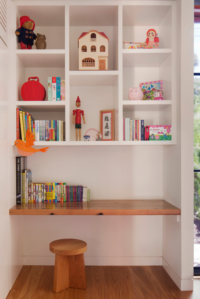 Ejemplo de habitación infantil unisex de 4 a 10 años actual con escritorio, paredes blancas y suelo de madera clara