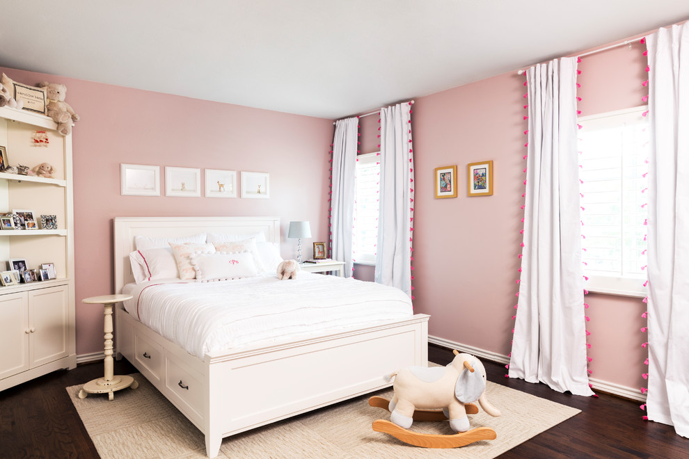Medium sized country children’s room for girls in Dallas with pink walls, brown floors and dark hardwood flooring.