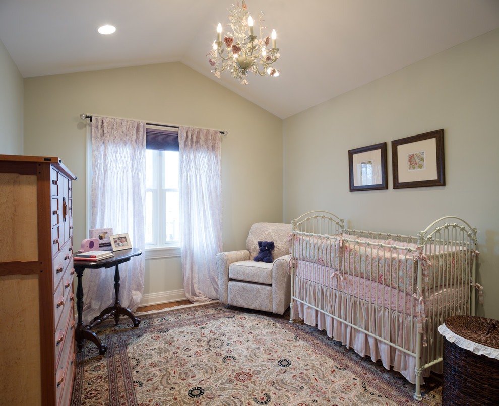 This is an example of a medium sized shabby-chic style toddler’s room for girls in Chicago with green walls and medium hardwood flooring.