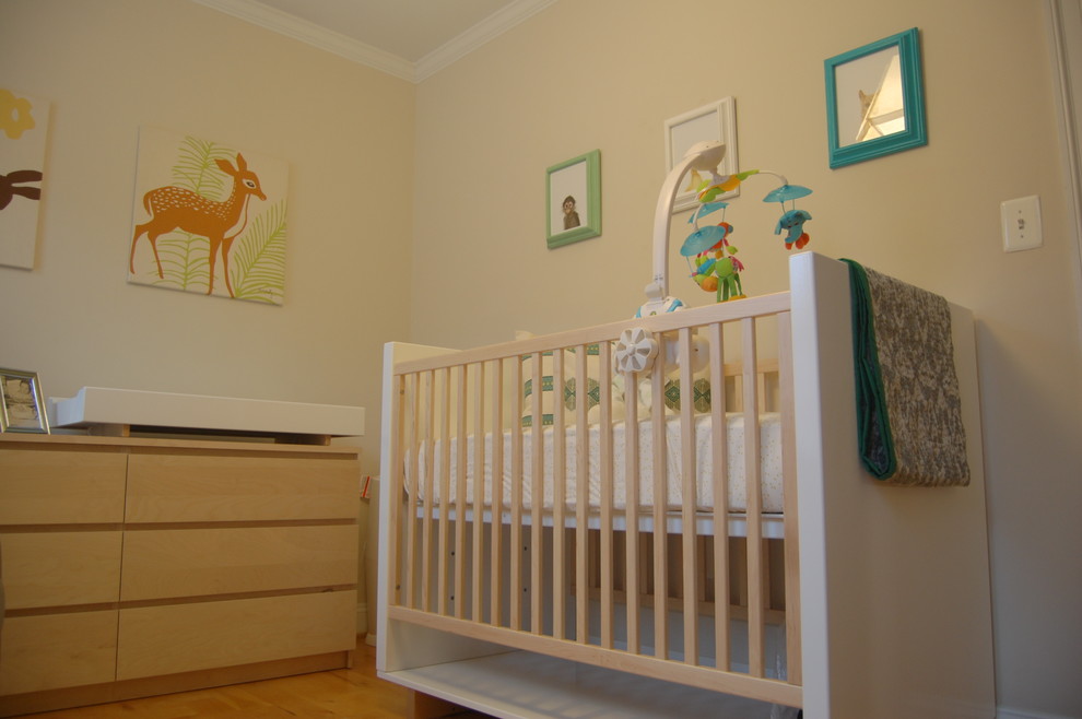 Diseño de habitación de bebé neutra moderna de tamaño medio con suelo de madera en tonos medios