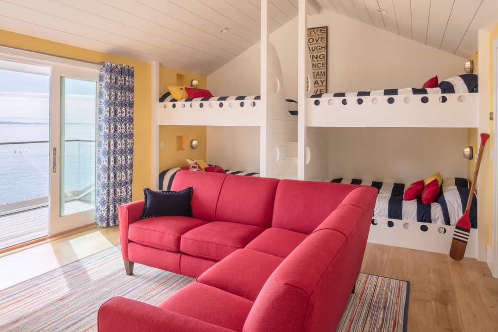 Idéer för maritima könsneutrala barnrum kombinerat med sovrum, med gula väggar, mellanmörkt trägolv och brunt golv