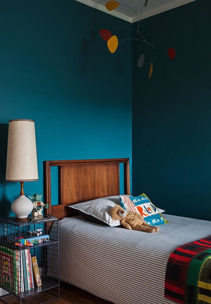 Cette image montre une chambre de garçon bohème avec un mur bleu et un sol en bois brun.