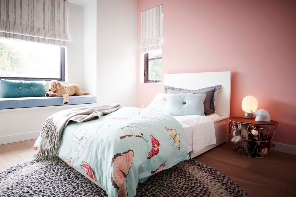 Esempio di una cameretta per bambini da 4 a 10 anni minimal di medie dimensioni con pareti rosa e parquet chiaro