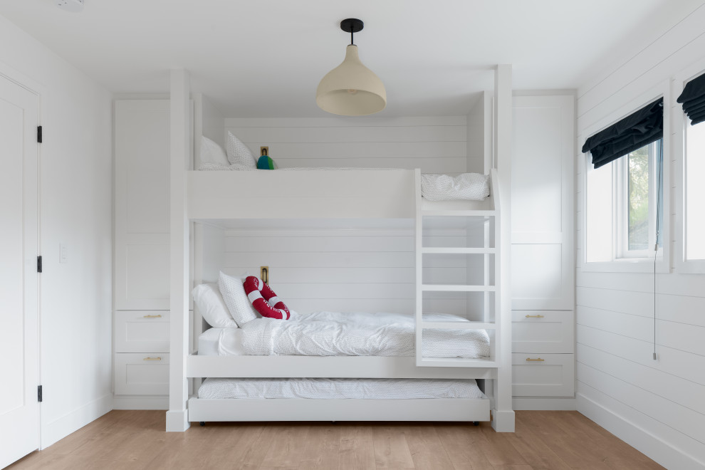 Modelo de dormitorio infantil costero de tamaño medio con paredes blancas y suelo marrón