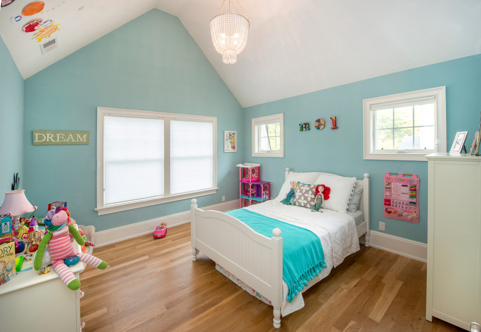 Photo of a medium sized classic kids' bedroom for girls in New York with blue walls and light hardwood flooring.