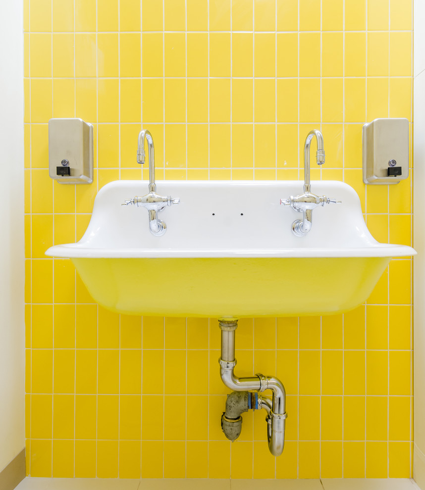 Inredning av ett modernt litet badrum, med gula väggar, laminatgolv och beiget golv