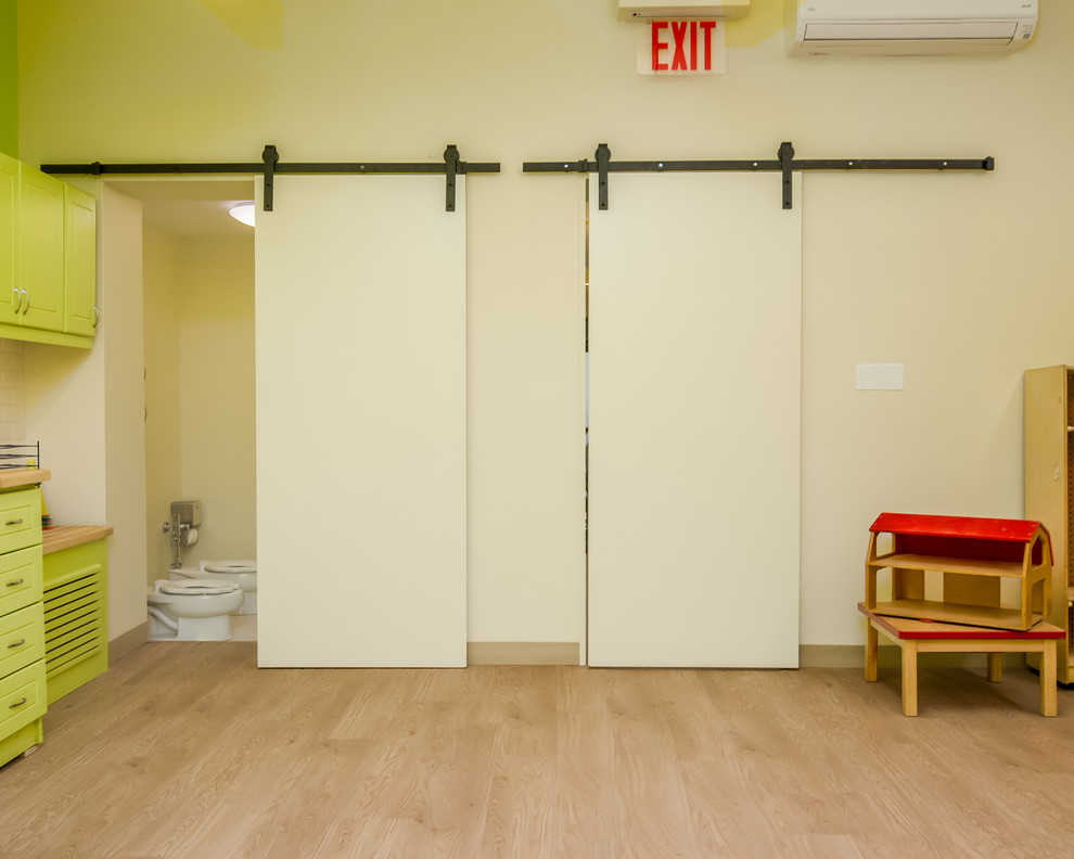 Kleines, Neutrales Modernes Kinderzimmer mit Spielecke, gelber Wandfarbe, Laminat und beigem Boden in New York