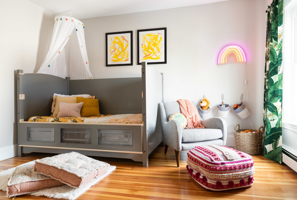 Immagine di una cameretta per bambini da 1 a 3 anni minimal di medie dimensioni con pareti grigie, pavimento in legno massello medio e pavimento marrone
