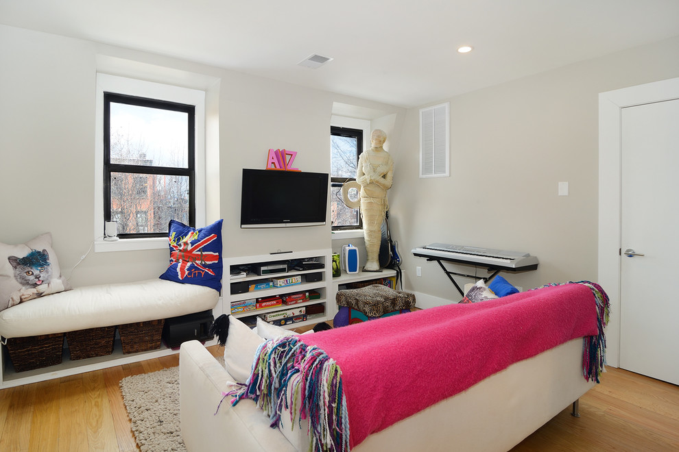 Eclectic gender neutral playroom in New York with beige walls and light hardwood flooring.