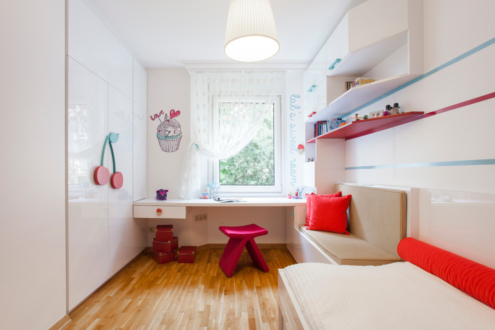 Immagine di una cameretta per bambini da 4 a 10 anni contemporanea con pareti bianche e pavimento in legno massello medio