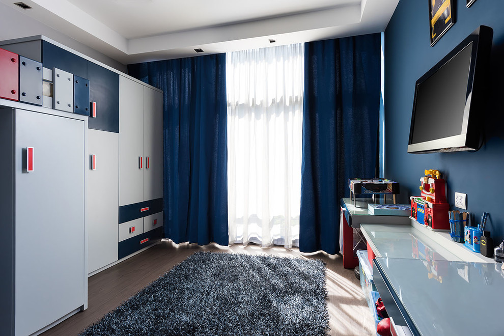 Immagine di una piccola cameretta per bambini da 4 a 10 anni contemporanea con pareti blu e parquet chiaro