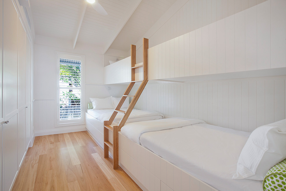 Exempel på ett mellanstort exotiskt könsneutralt barnrum kombinerat med sovrum, med vita väggar och ljust trägolv