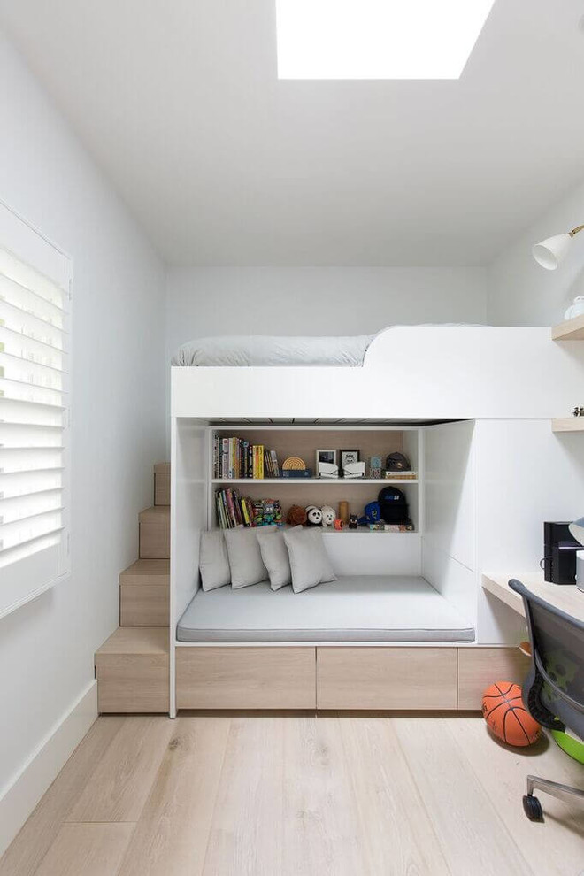 Diseño de dormitorio infantil actual con paredes blancas, suelo de madera clara y suelo beige