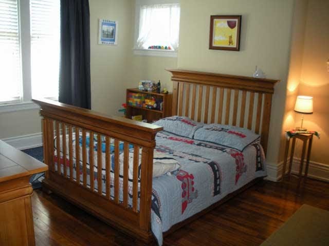 Cette photo montre une chambre d'enfant de 1 à 3 ans craftsman de taille moyenne avec un mur jaune et un sol en bois brun.