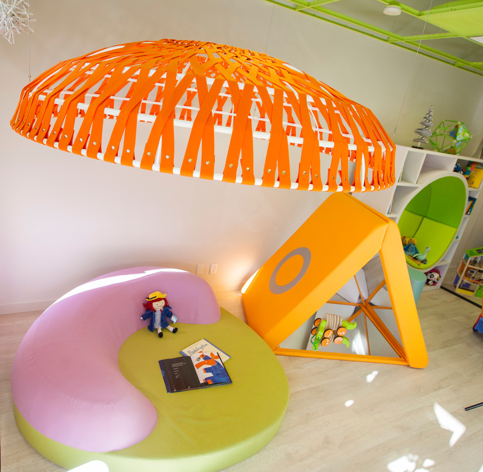 Example of a large minimalist gender-neutral light wood floor kids' room design in Omaha with white walls