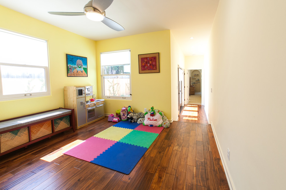 Exempel på ett mellanstort klassiskt könsneutralt småbarnsrum kombinerat med lekrum, med gula väggar, mellanmörkt trägolv och brunt golv