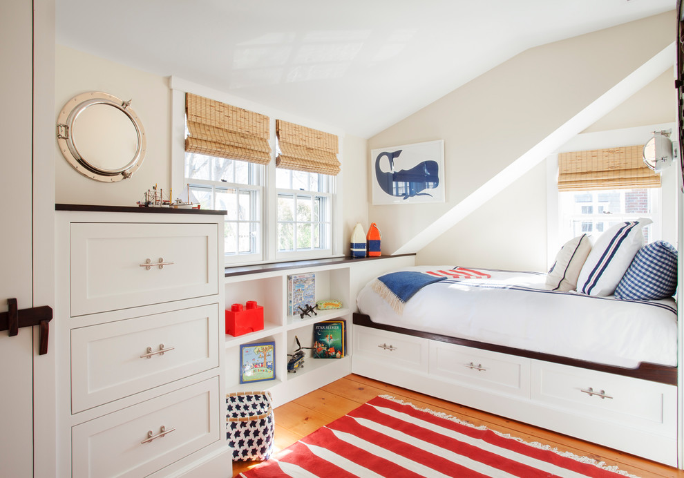 This is an example of a coastal kids' bedroom in Boston with white walls and medium hardwood flooring.