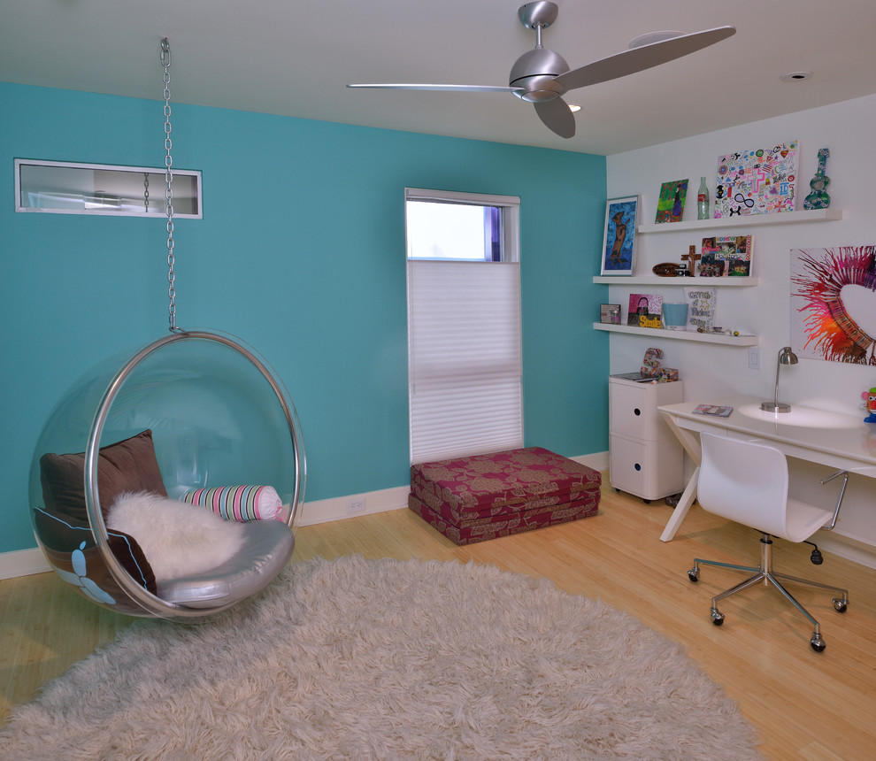 Inredning av ett modernt könsneutralt tonårsrum kombinerat med skrivbord, med blå väggar och ljust trägolv
