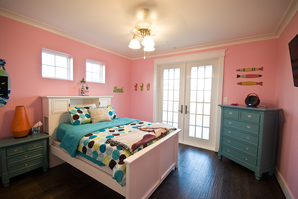 Modelo de dormitorio infantil costero de tamaño medio con paredes rosas y suelo de madera oscura
