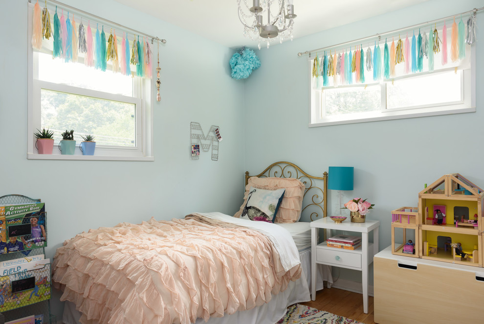 This is an example of a small classic children’s room for girls in DC Metro with blue walls and light hardwood flooring.