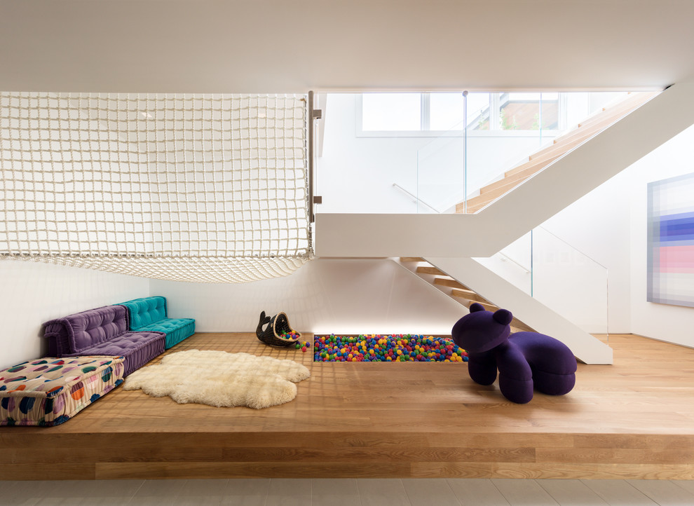 Großes, Neutrales Modernes Kinderzimmer mit Spielecke, weißer Wandfarbe, braunem Holzboden und braunem Boden in Sonstige
