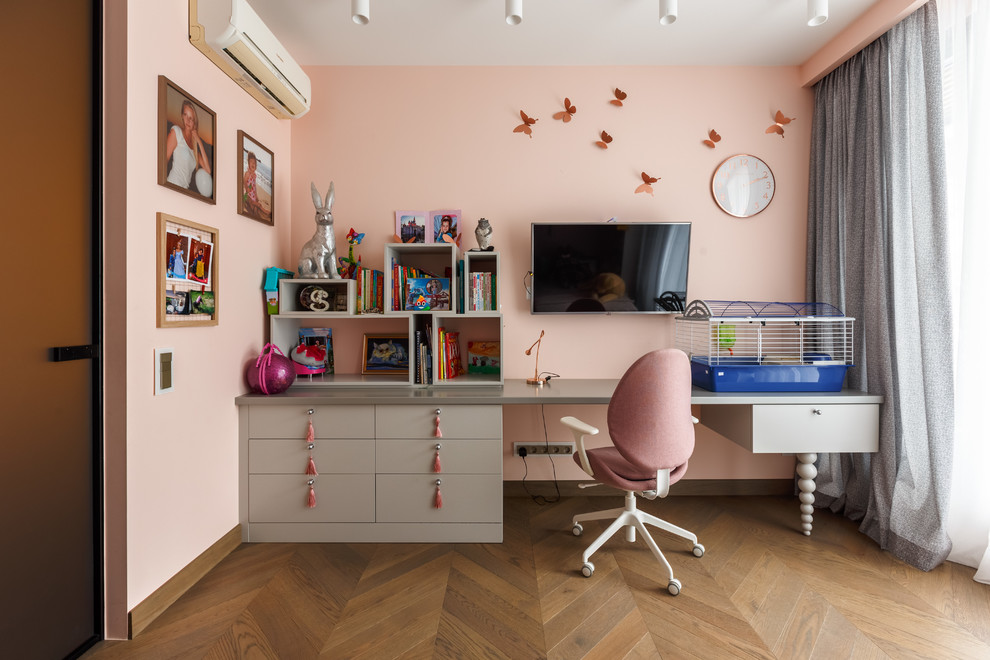 Modelo de habitación de niña contemporánea con escritorio, paredes rosas, suelo de madera en tonos medios y suelo marrón