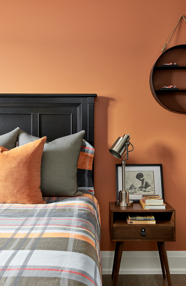 Bild på ett vintage pojkrum kombinerat med sovrum, med orange väggar, mellanmörkt trägolv och brunt golv